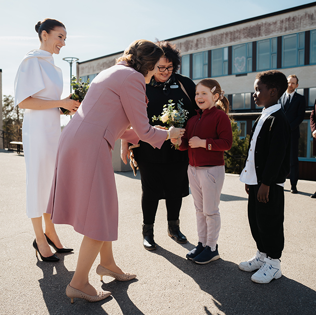 Drottningen och fru Innes-Stubb välkomnas av elever utanför Sätraskolan.