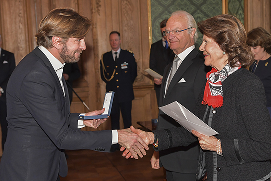 Regissör Ruben Östlund tar emot diplom av Drottningen efter att ha tagit emot H.M. Konungens medalj i 8:e storleken i högblått band "för betydande insatser inom svensk film". 