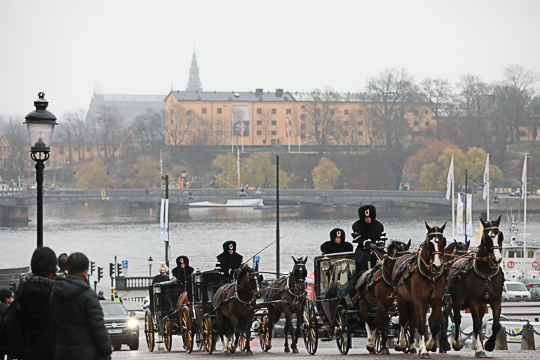 Ambassadörerna med följe färdas i Hovstallets vagnar uppför Slottsbacken vid Kungliga slottet.