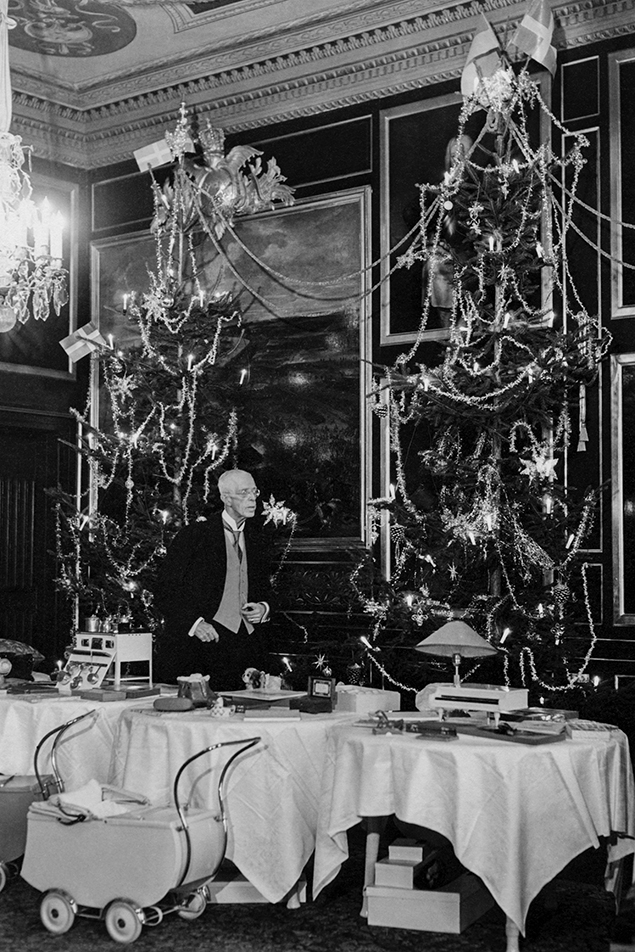Kung Gustaf V fotograferad i Generalssalen på Drottningholm vid ett julfirande på 40-talet. Julklapparna ligger oinslagna på borden, enligt Kungafamiljens dåvarande tradition. Gustaf V var den kung som inledde traditionen att fira hela julen på Drottningholm. Hans föräldrar, kung Oskar II och drottning Sofia, firade julafton på Kungliga slottet för att därefter bege sig till Drottningholm. 
