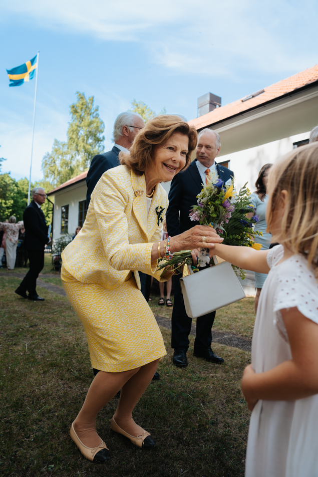 Drottningen får blommor från en liten flicka vid Svenskbygården.