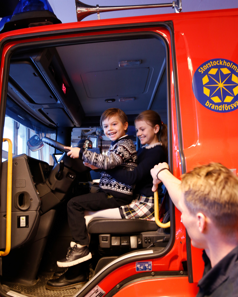 Princess Estelle and Prince Oscar sit in a fire engine. 