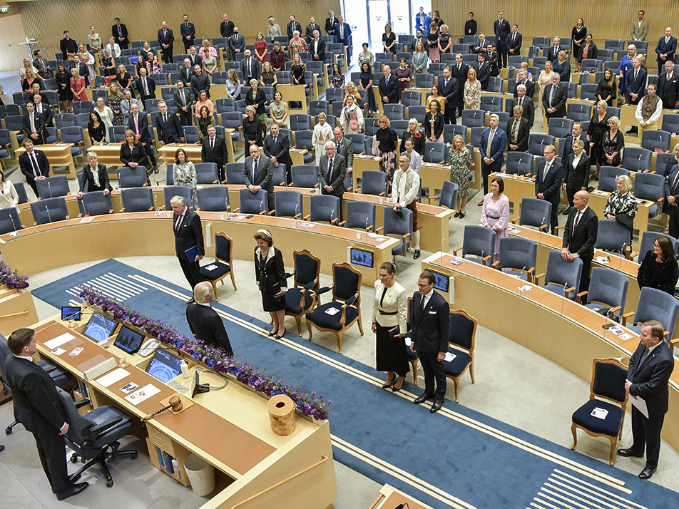 The King greets the members of the Riksdag in the chamber. 