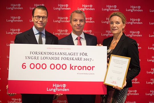 Prins Daniel och Hjärt- och Lungfondens generalsekreterare Kristina Sparreljung överlämnar checken på sex miljoner kronor till docent Mattias Carlström. 