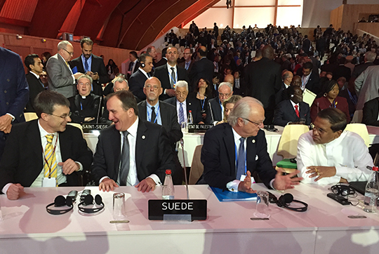 Kungen och statsministern vid den svenska delegationens bord. Kungen samtalar med en delegat från Sri Lanka.