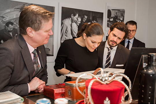 Kronprinsessan, Prins Carl Philip och Prins Daniel tittar på arkivmaterial tillsammans med Centrum för Näringslivshistorias vd Alexander Husebye.