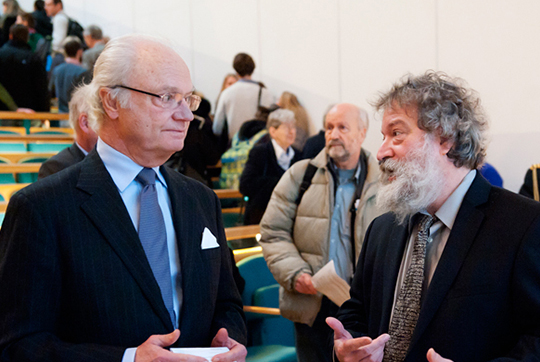 Kungen i samtal med professor Raymond Pierrehumbert vid föreläsningen på Stockholms universitet.