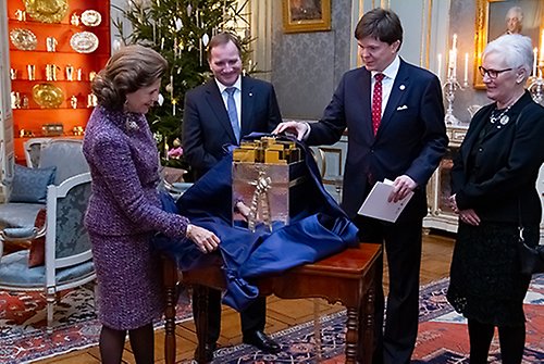 Drottningen öppnar gåvan från Sveriges riksdag och regering som överlämnades av statsminister Stefan Löfven, talman Andreas Norlén och första vice talman Åsa Lindestam. 