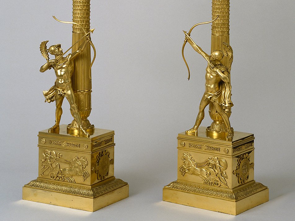Två kandelabrar med bågskyttar i antik dräkt. Förgylld brons. Franskt arbete från 1810-talet. Empire.