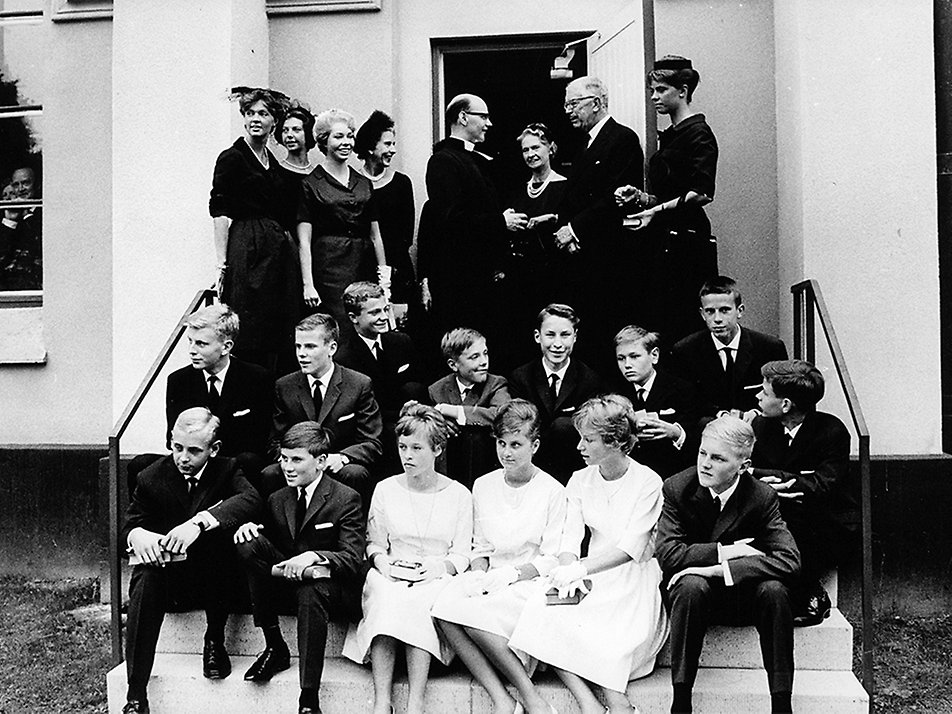 Kungen i samband med sin konfirmation på Öland. I bakgrunden syns kung Gustaf VI Adolf, drottning Ingrid av Danmark, prinsessan Sibylla och Kungens systrar.