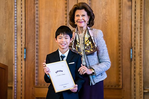 Drottningen tillsammans med Vincent Wang, en av de vinnande majblommesäljarna från Adolf Fredriks Musikklasser. 